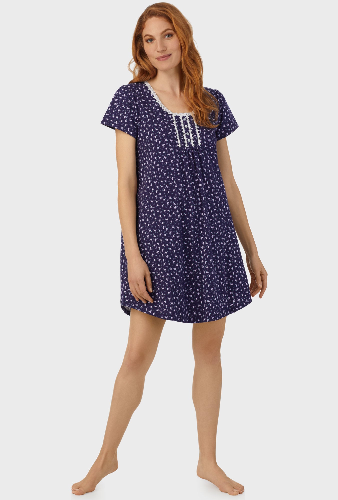 A lady wearing navy cap sleeve nightshirt with midnight blue ditsy floral print.