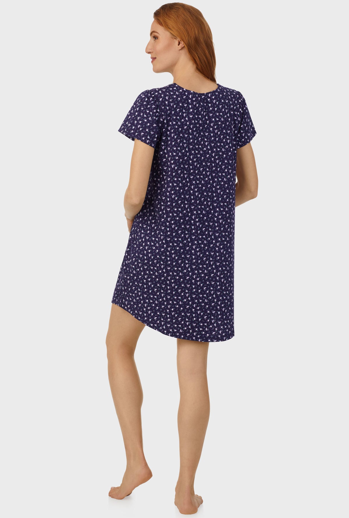 A lady wearing navy cap sleeve nightshirt with midnight blue ditsy floral print.