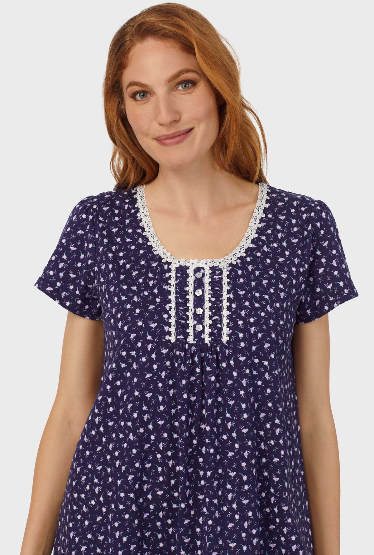 A lady wearing navy cap sleeve nightshirt with midnight blue ditsy floral print.