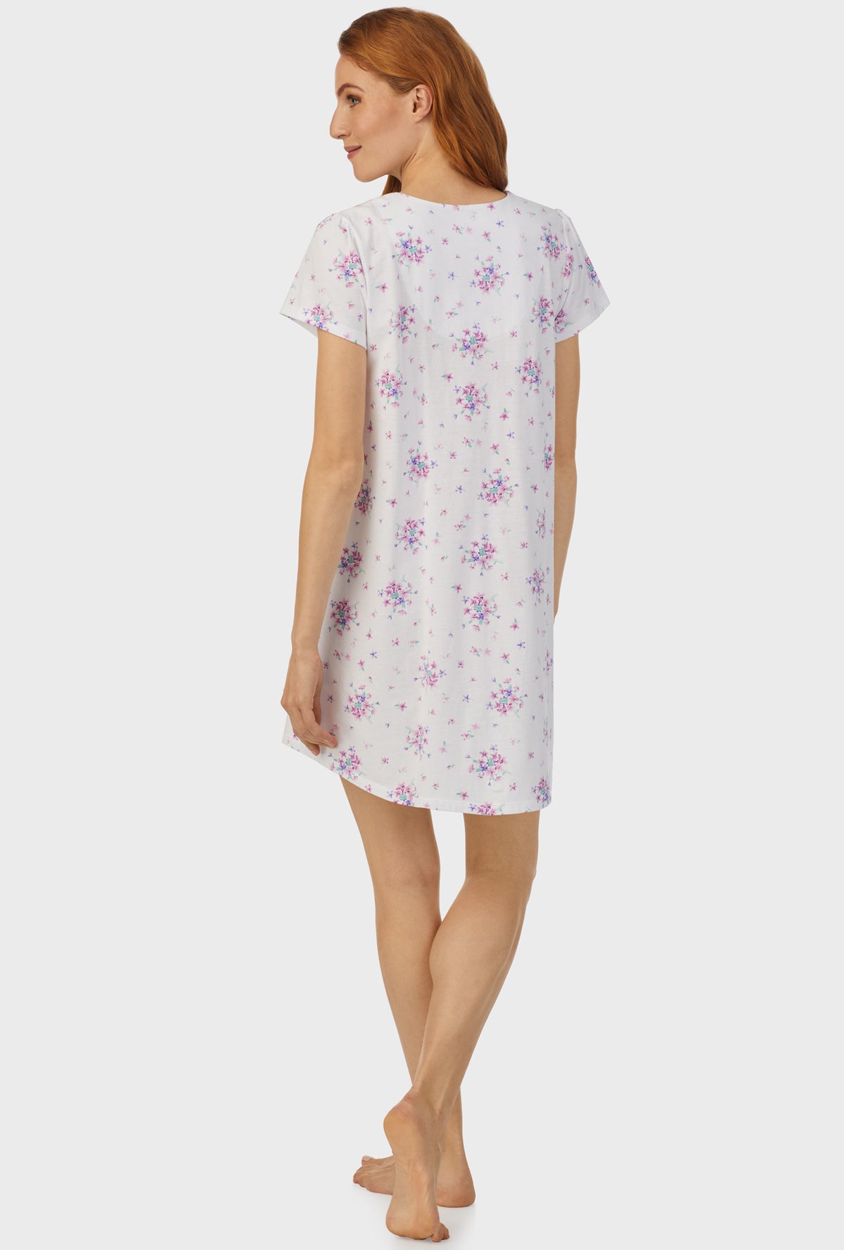 A lady wearing white cap sleeve nightshirt  with mulberry purple floral print bouquet.