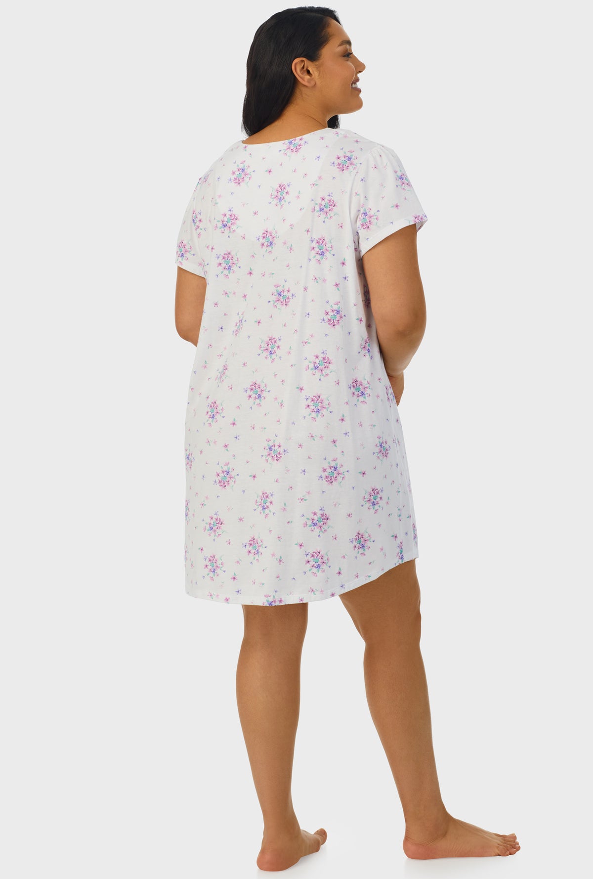 A lady wearing white cap sleeve plus size nightshirt with mulberry purple floral print bouquet.