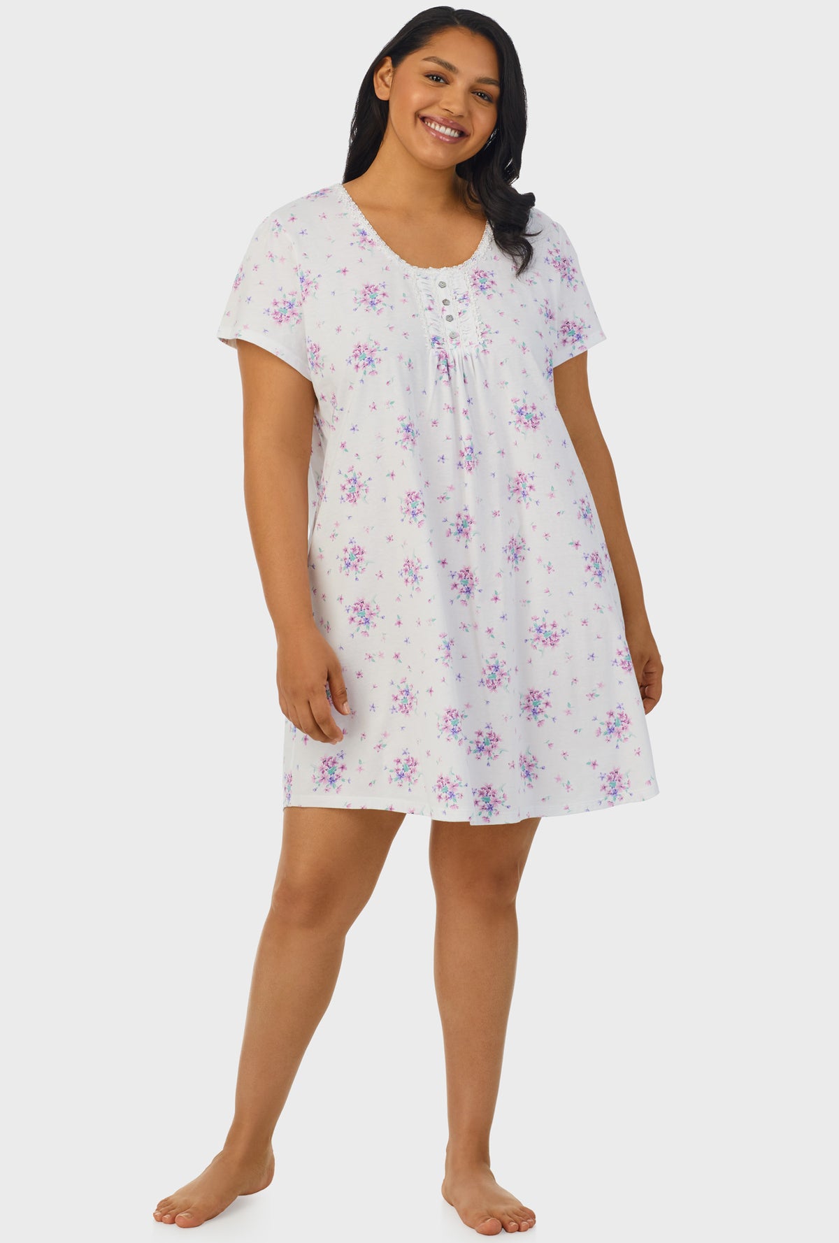 A lady wearing white cap sleeve plus size nightshirt with mulberry purple floral print bouquet.