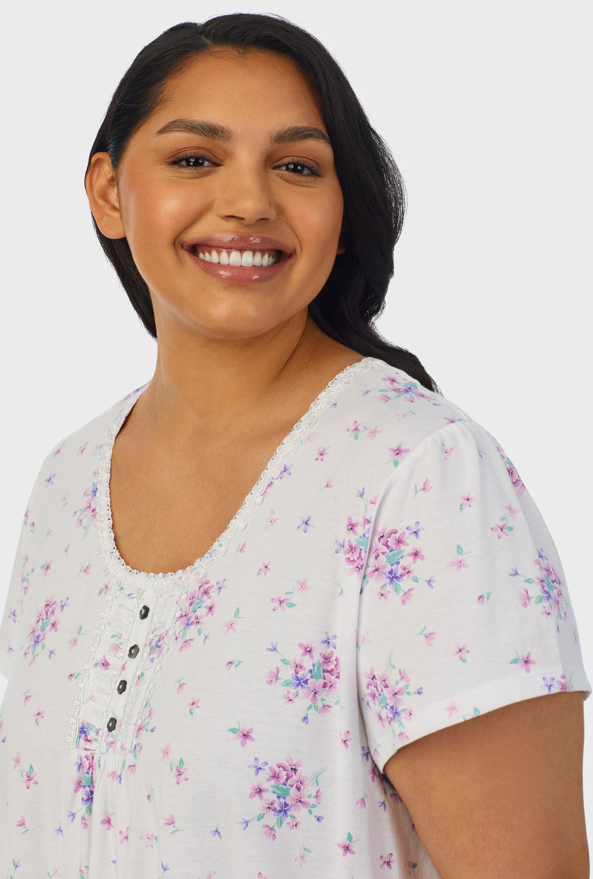 A lady wearing white cap sleeve plus size nightshirt with mulberry purple floral print bouquet.