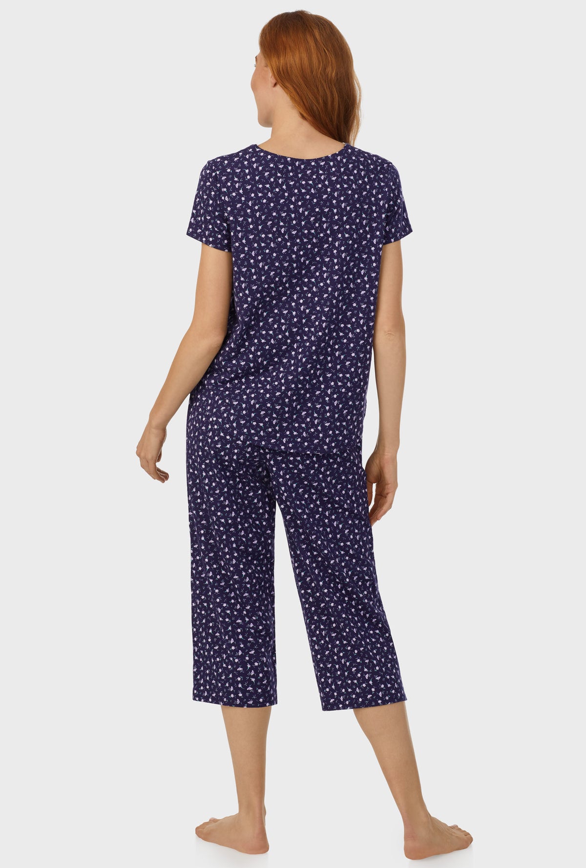 A lady wearing navy short sleeve capri pant pj set with midnight blue ditsy floral print.