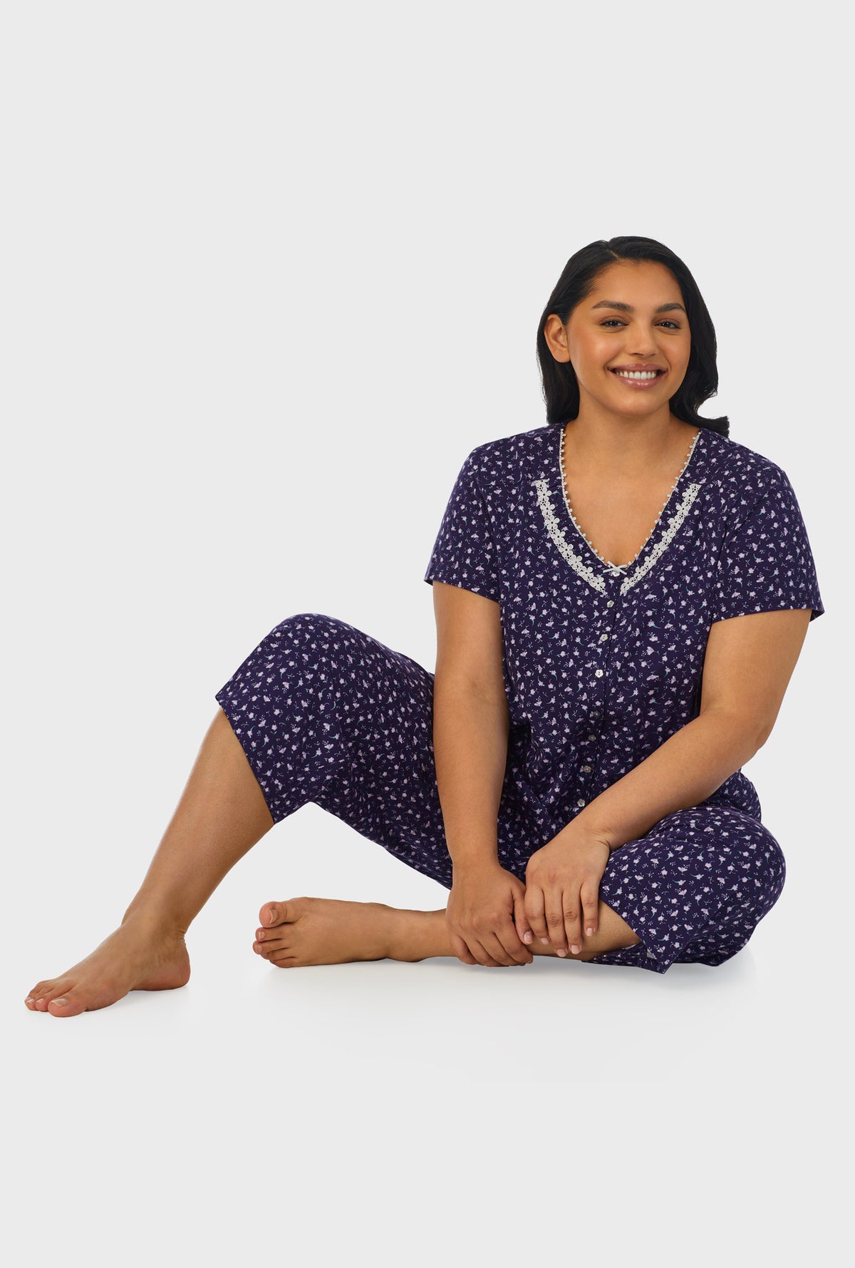 A lady wearing navy short sleeve capri plus size pant pj set with midnight blue ditsy floral print.