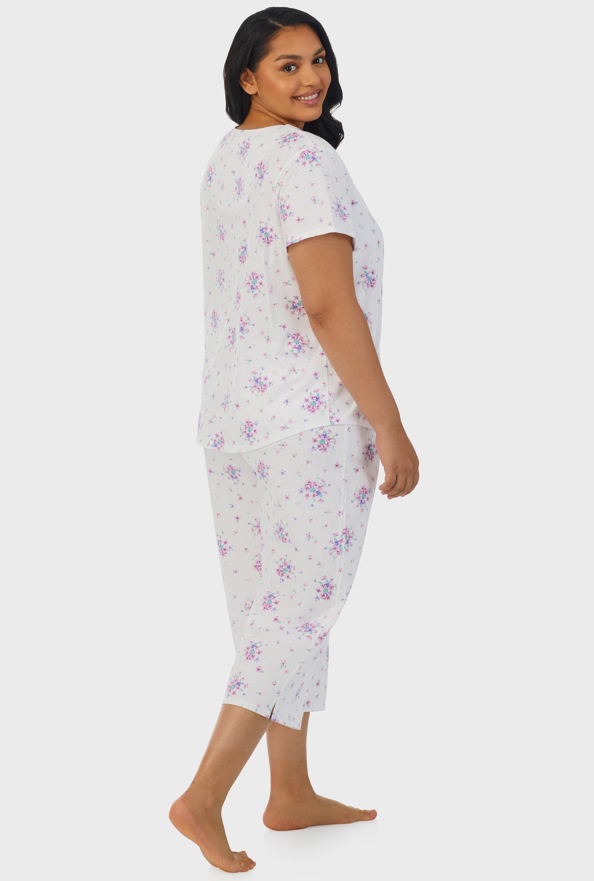 A lady wearing purple short sleeve capri pant plus size pj set with mulberry purple floral bouquet print.