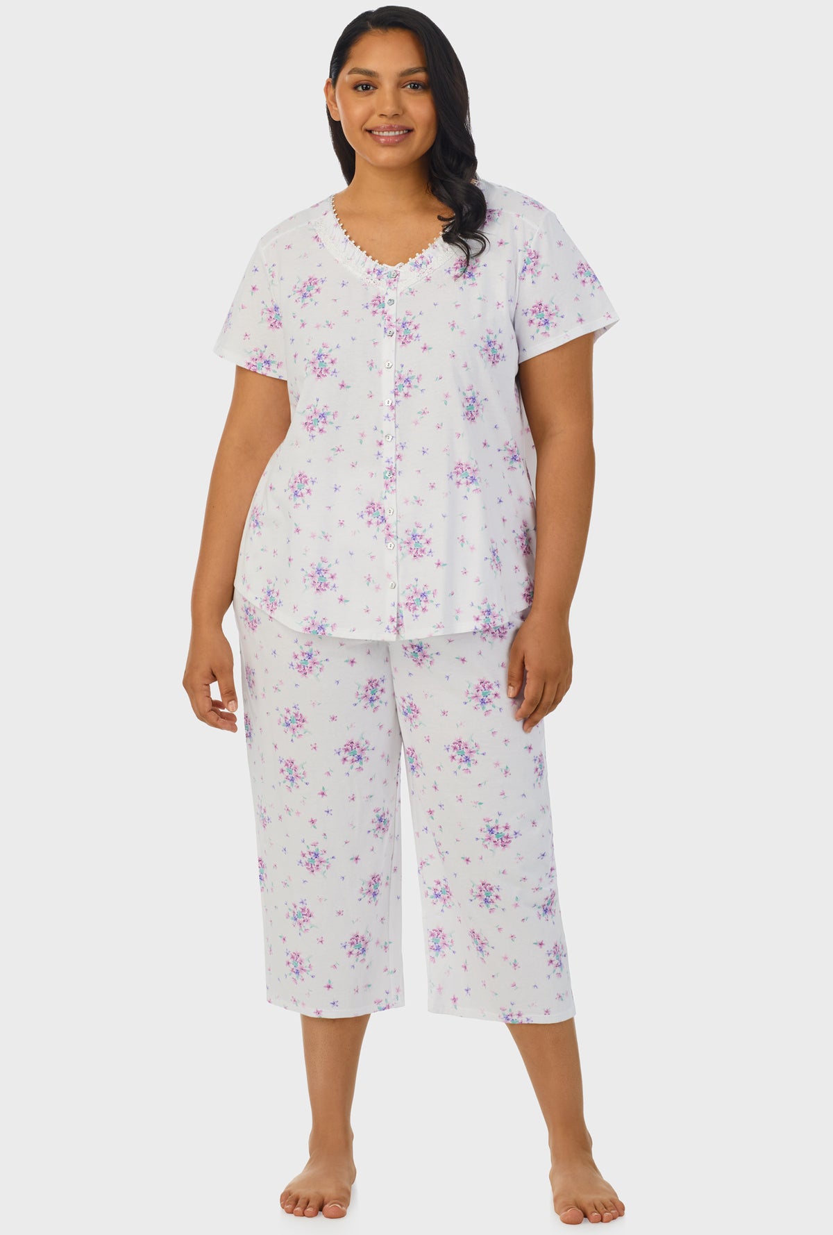 A lady wearing purple short sleeve capri pant plus size pj set with mulberry purple floral bouquet print.