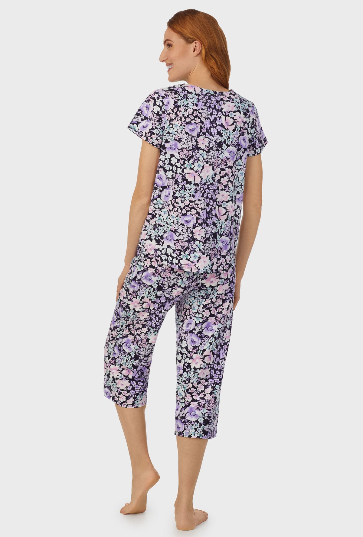 A lady wearing navy short sleeve capri pant pj set  with midnight blue floral print.