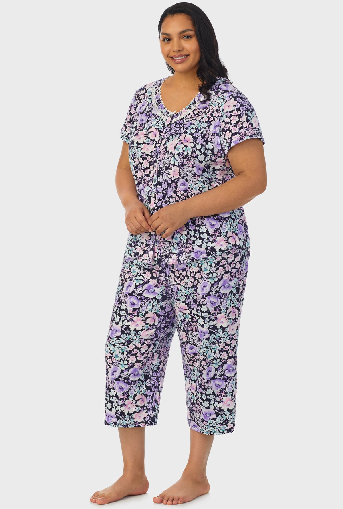 A lady wearing navy short sleeve capri pant plus size pj set with midnight blue floral print.