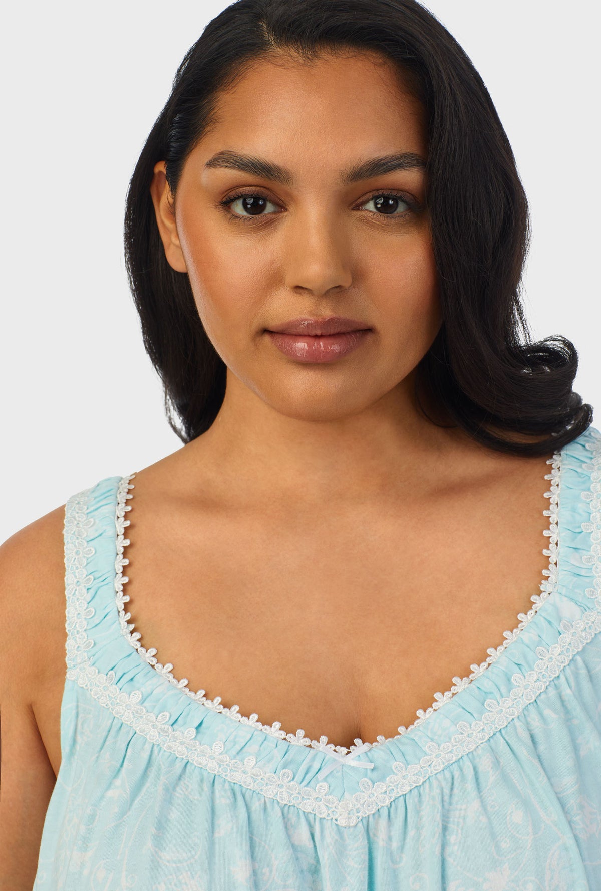 A lady wearing aqua sleeveless plus size chemise with scroll print.