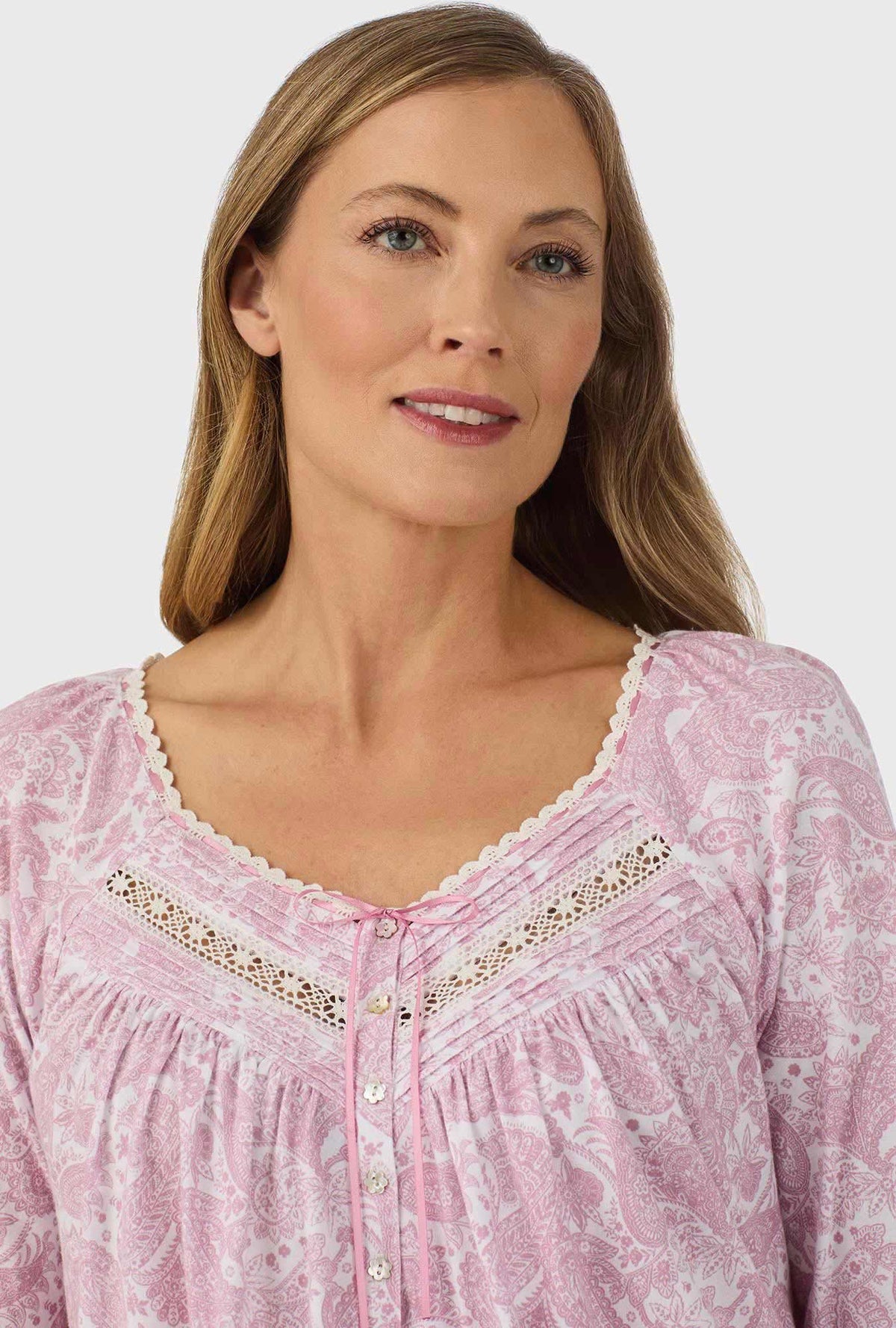 A lady wearing pink long sleeve nightgown with pink paisley print.