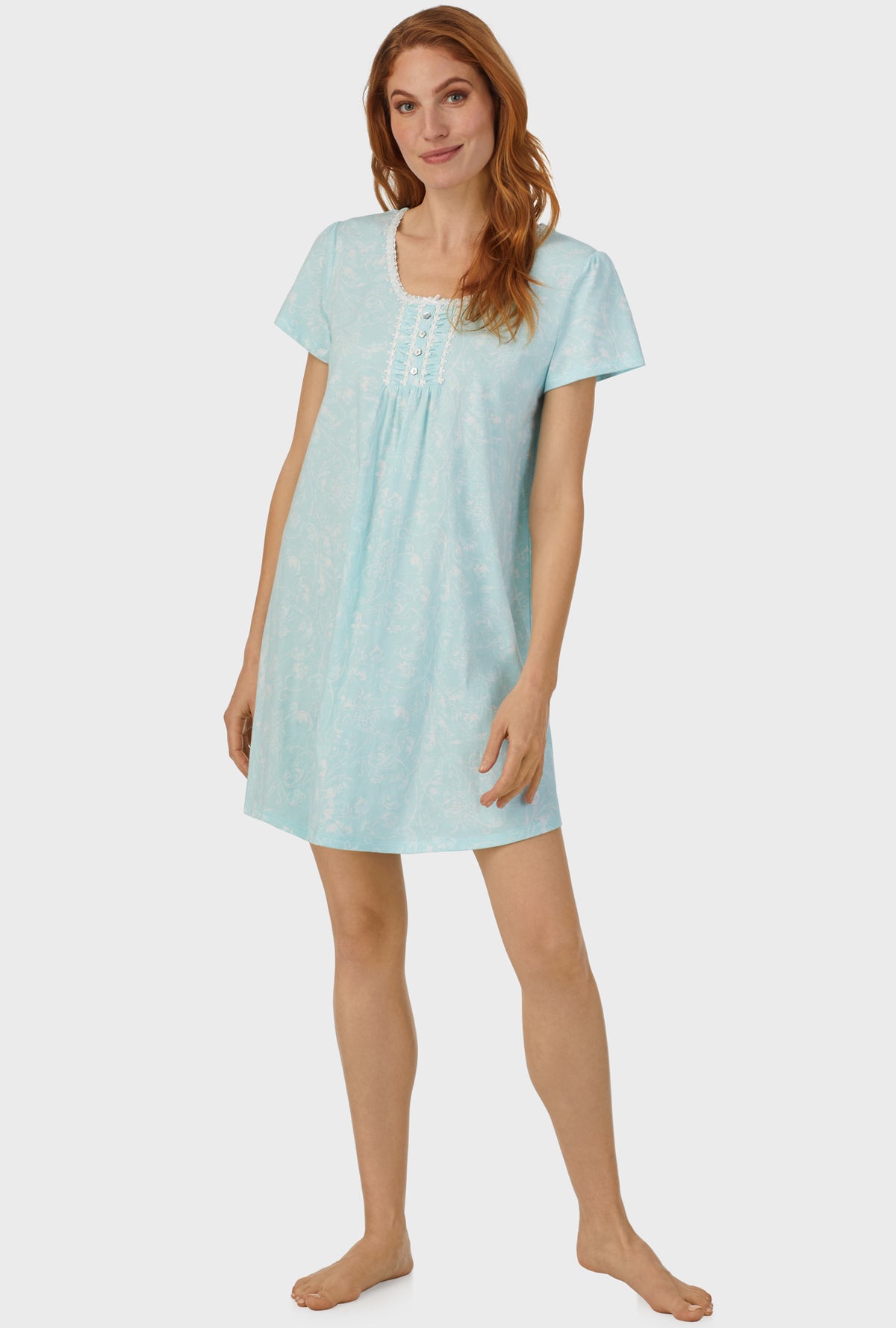 A lady wearing blue cap sleeve nightshirt with aqua scroll print.