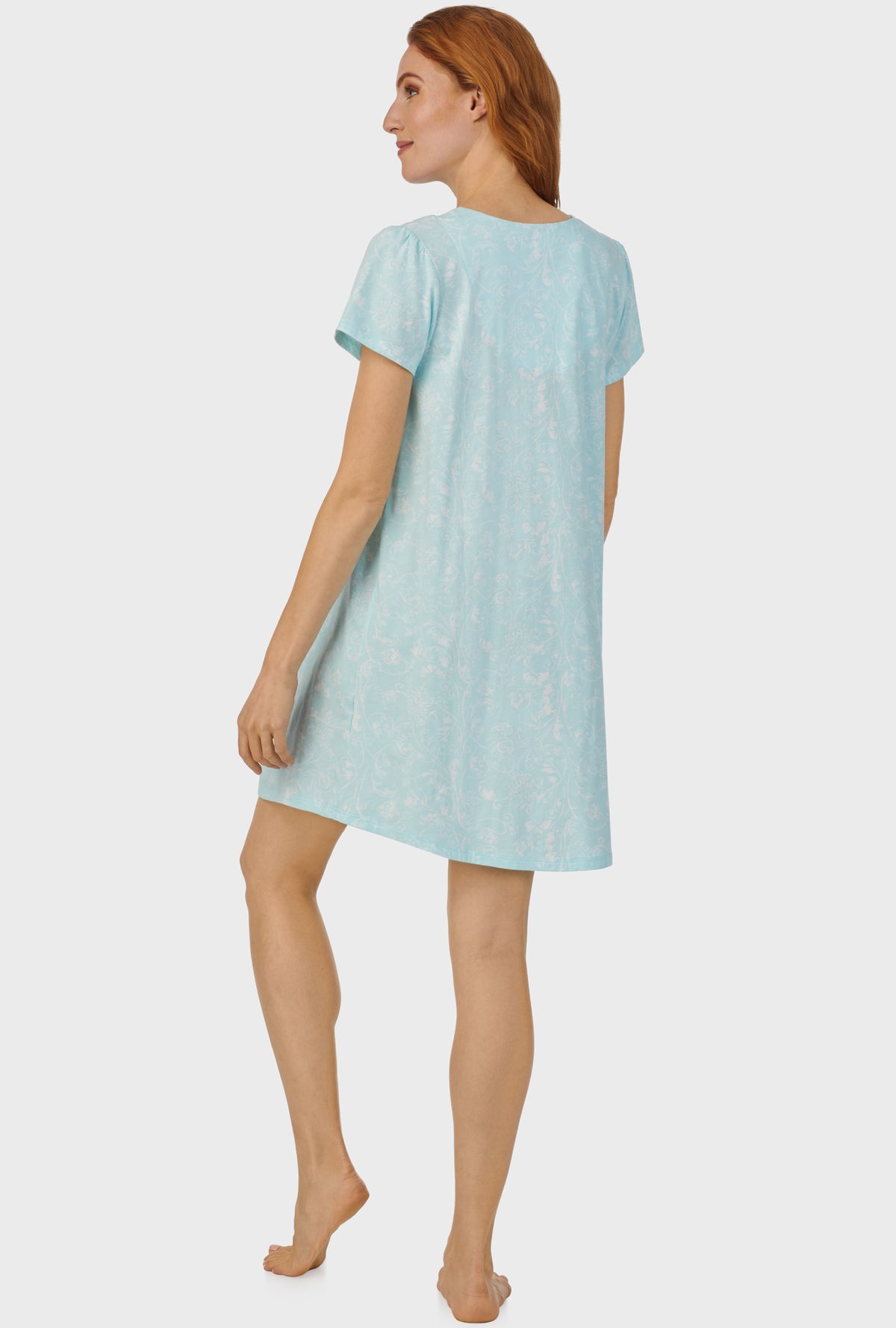 A lady wearing blue cap sleeve nightshirt with aqua scroll print.