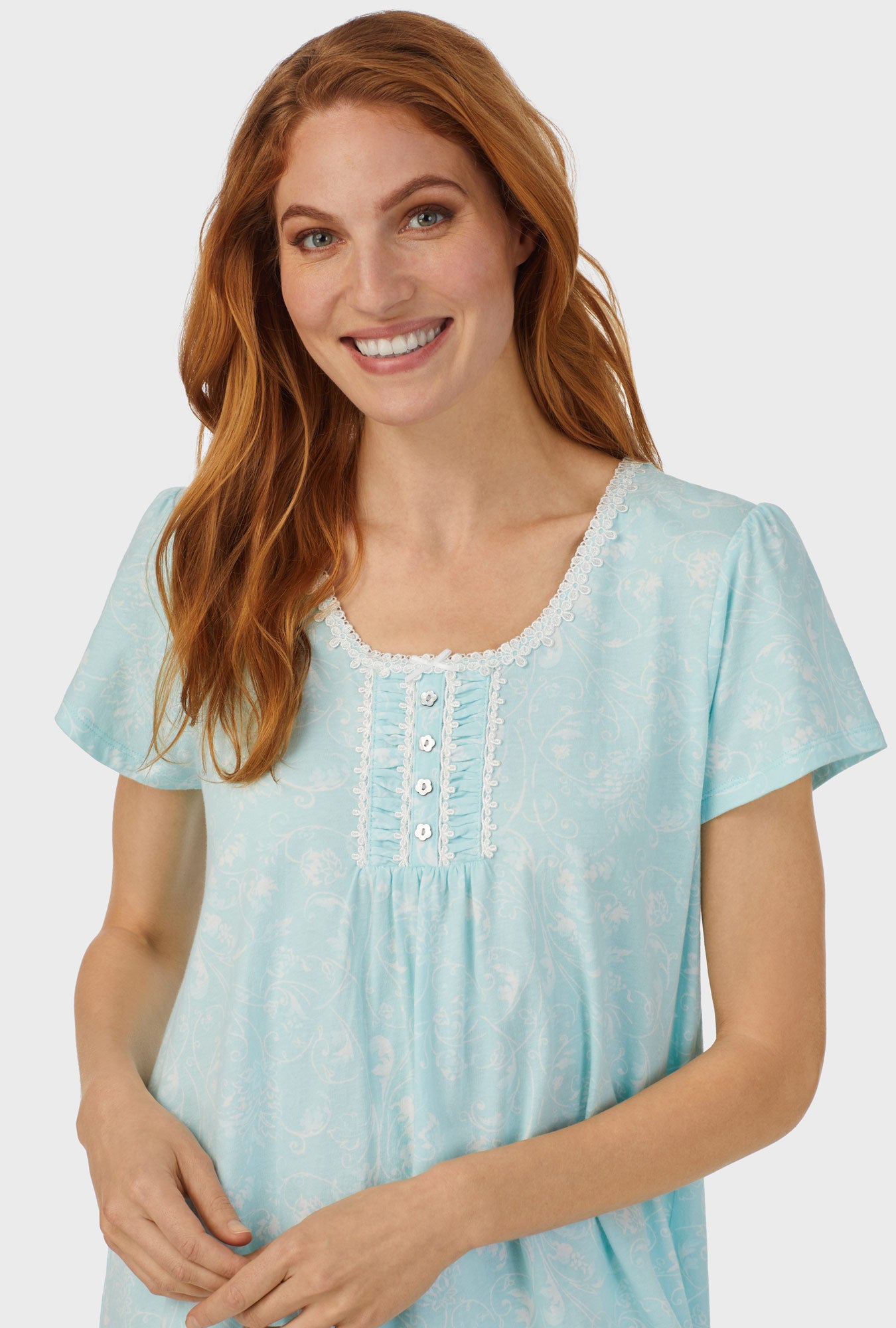A lady wearing blue cap sleeve nightshirt with aqua scroll print.