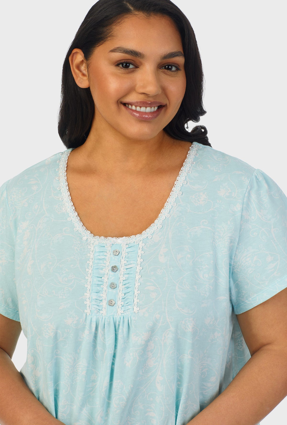 A lady wearing blue cap sleeve plus size nightshirt with aqua scroll print.