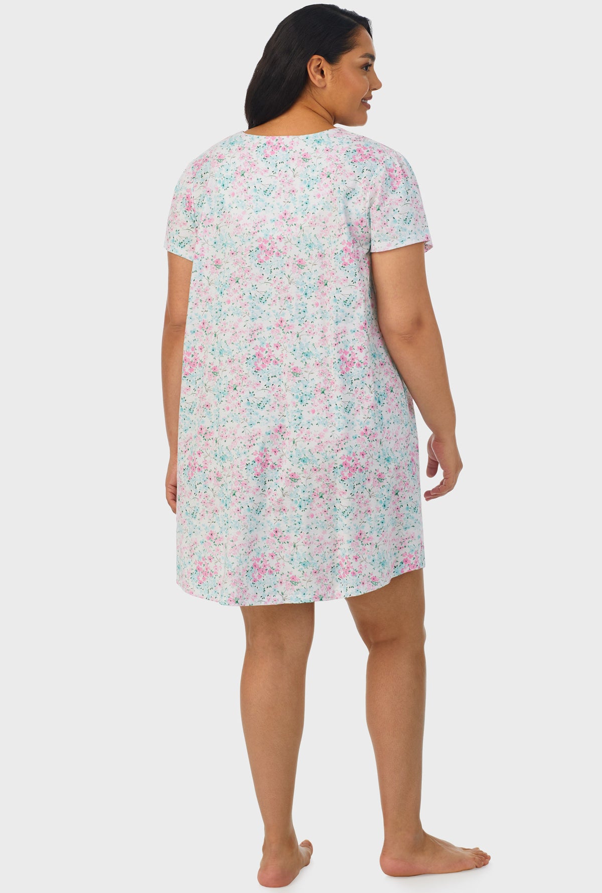 A lady wearing white cap sleeve plus size nightshirt with aqua and pink floral print.