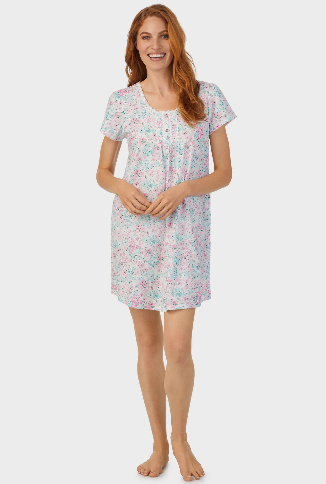 A lady wearing white cap sleeve nightshirt with aqua and pink floral print.