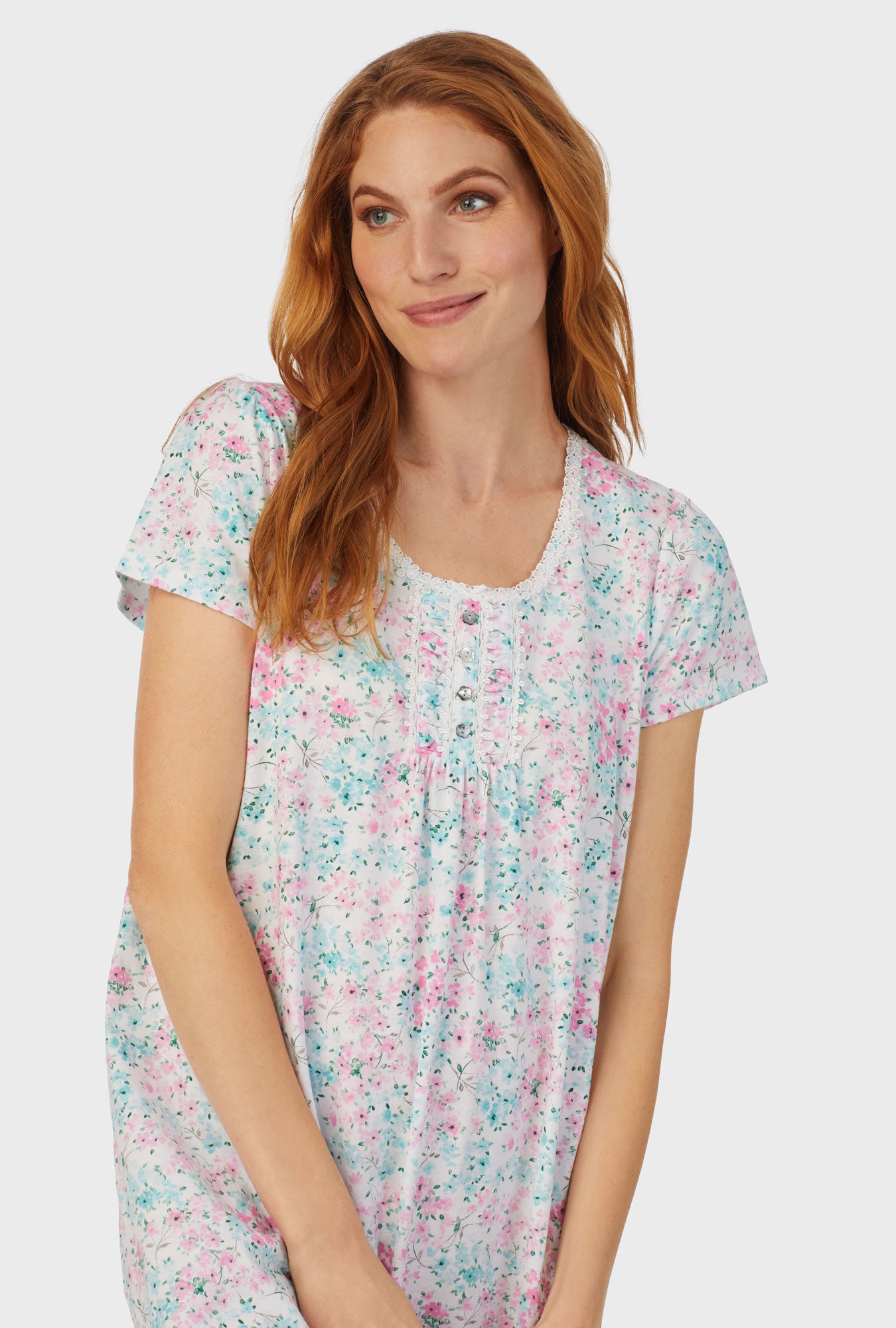 A lady wearing white cap sleeve nightshirt with aqua and pink floral print.