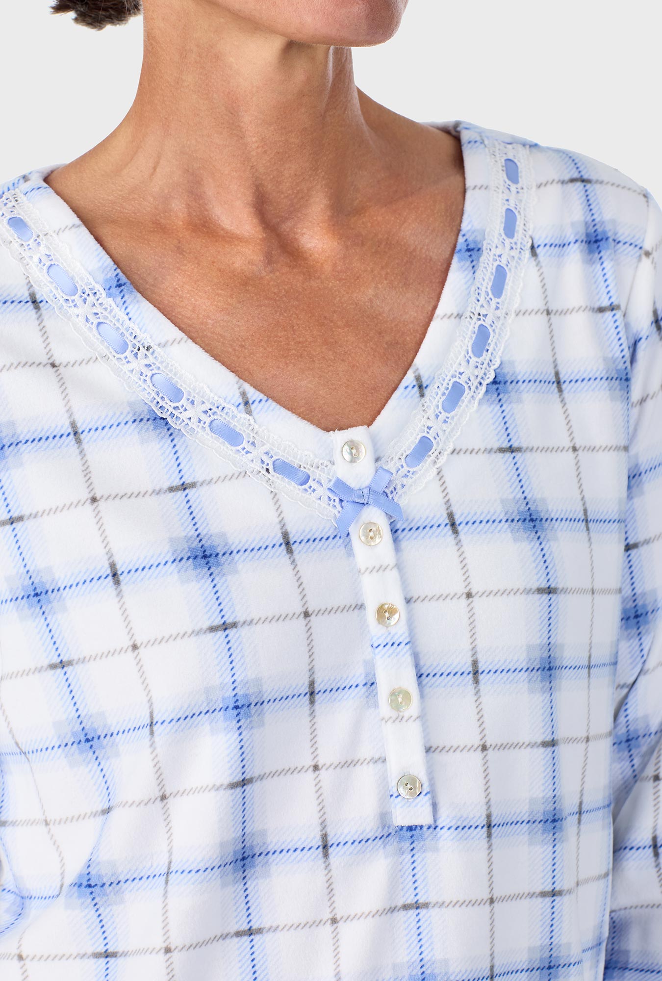 A lady wearing blue long sleeve Henley  pj set with blue bell plaid print.