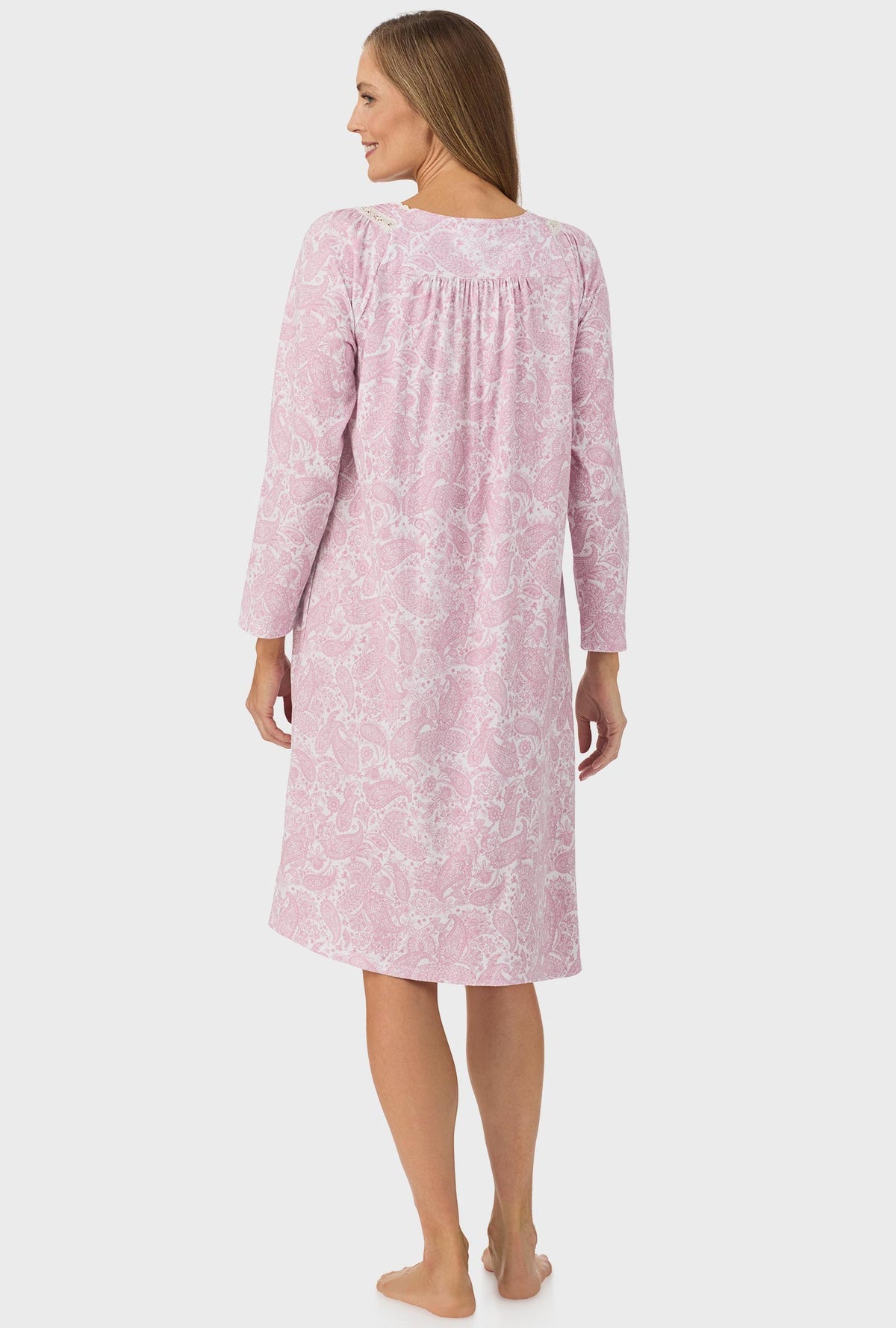 A lady wearing pink long sleeve nightgown with pink paisley print.