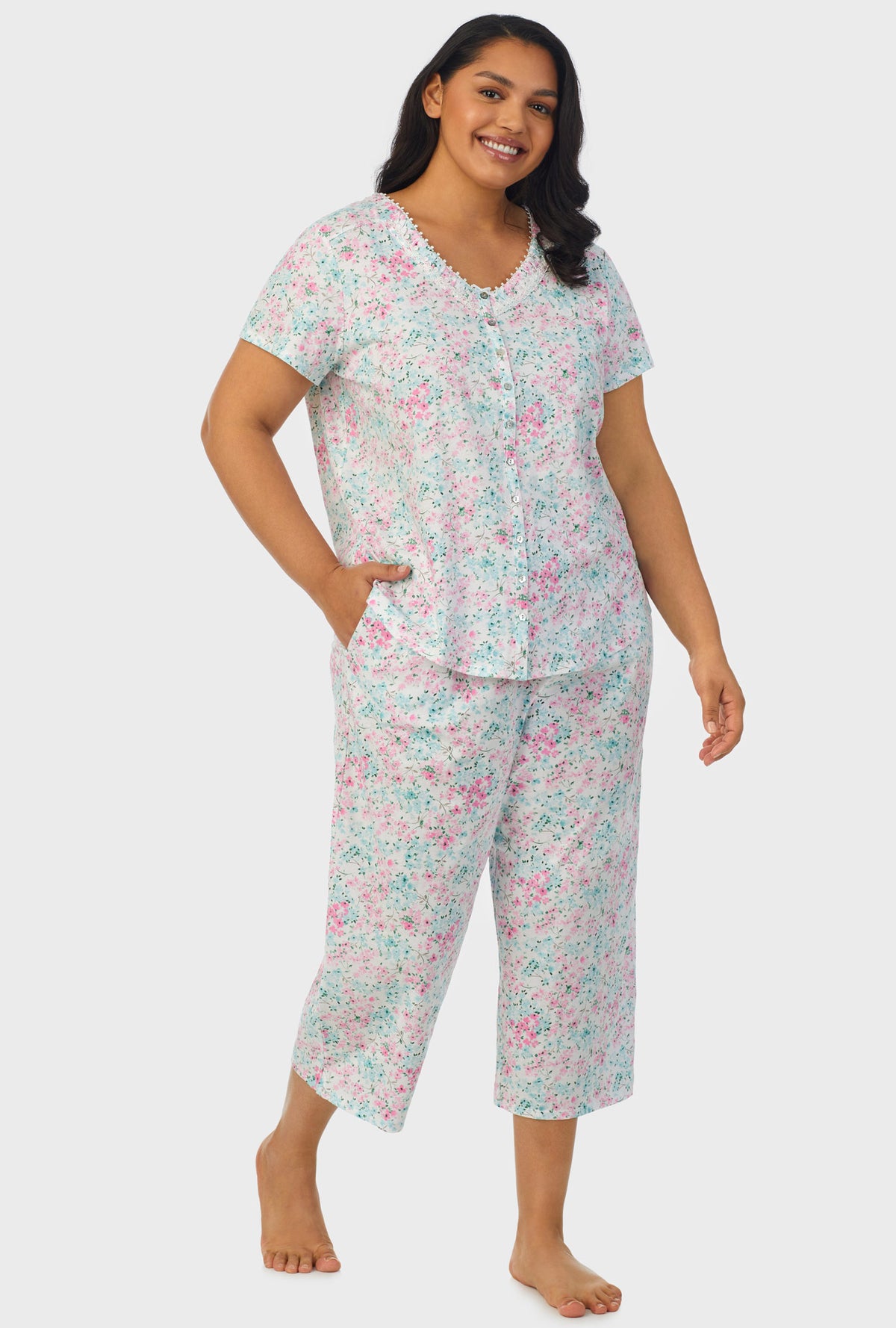 A lady wearing multi color short sleeve capri pant plus size pj set with aqua and pink floral print.