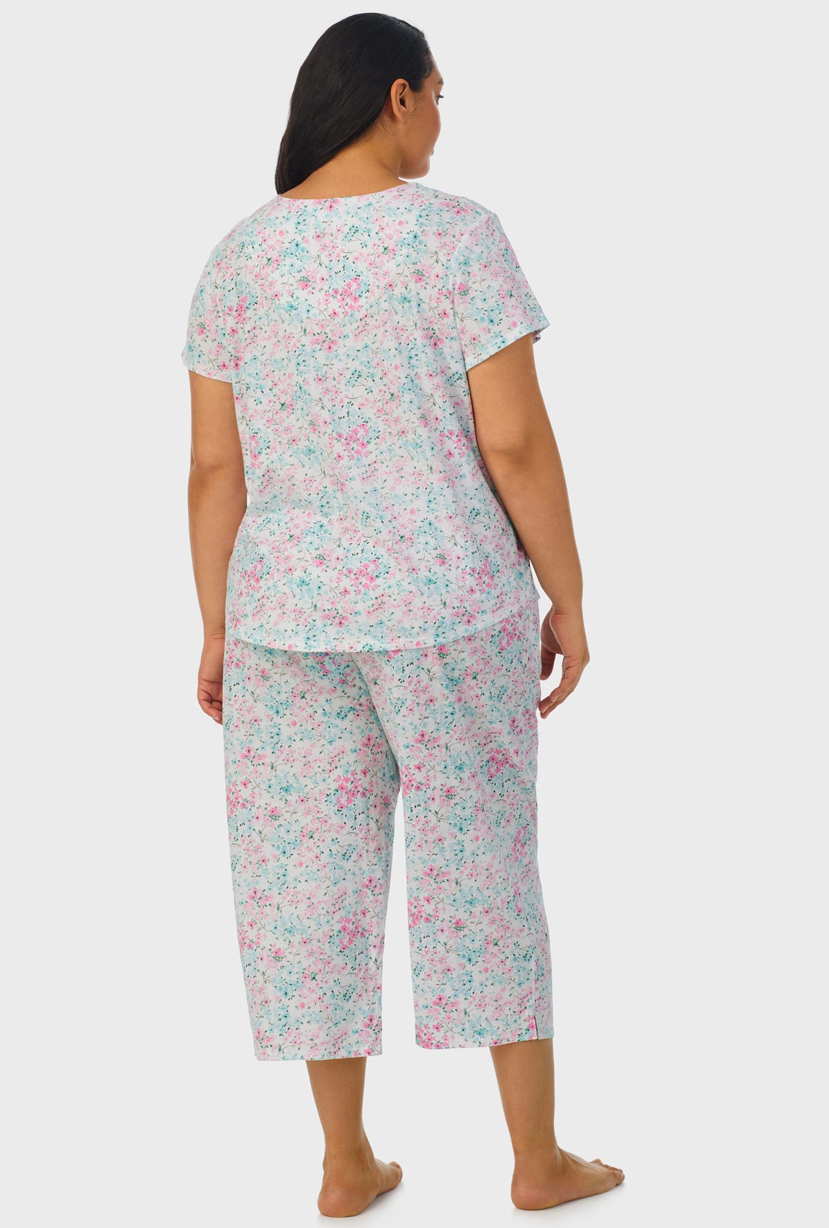 A lady wearing multi color short sleeve capri pant plus size pj set with aqua and pink floral print.