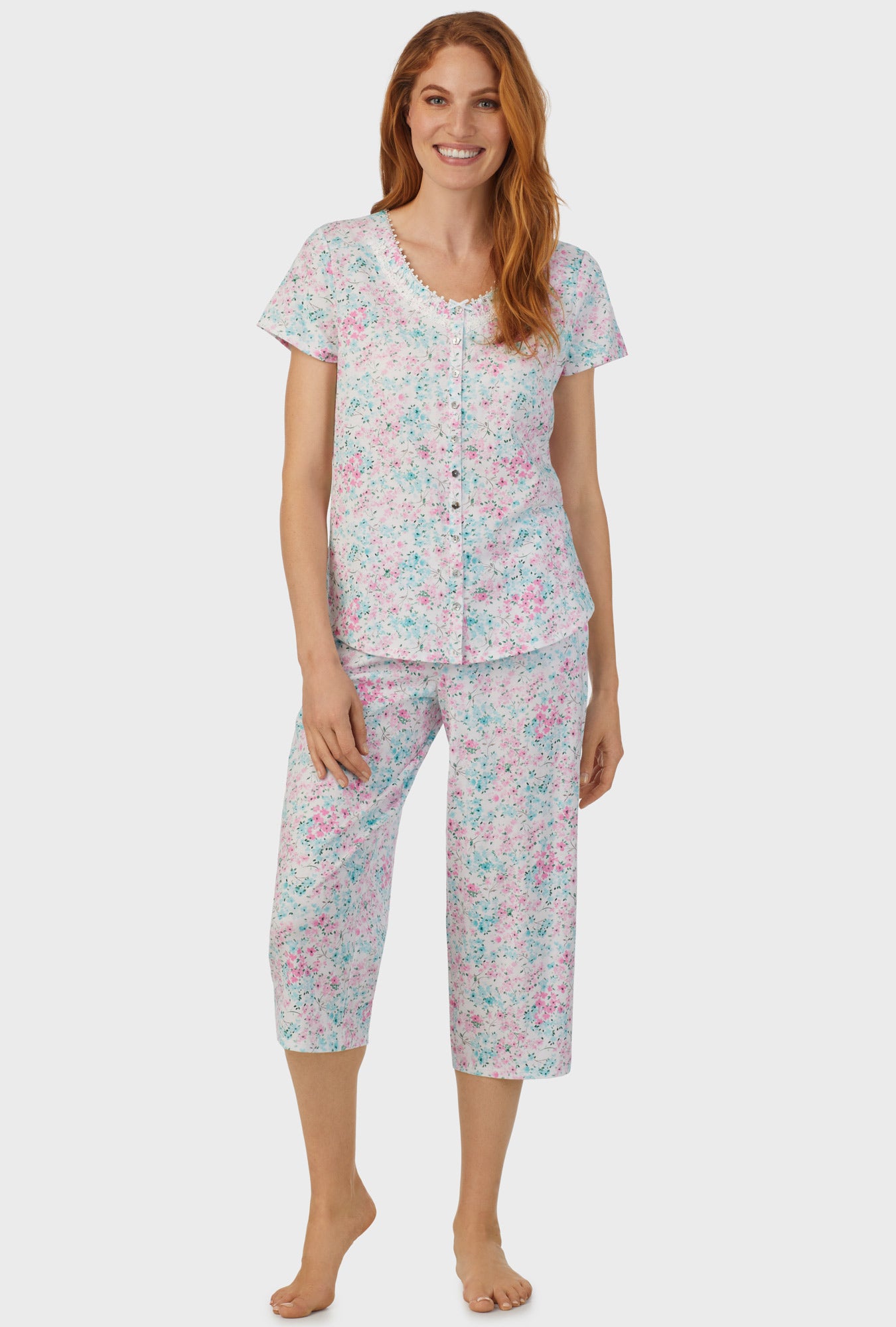 A lady wearing multi color short sleeve capri pant pj set with aqua and pink floral print.