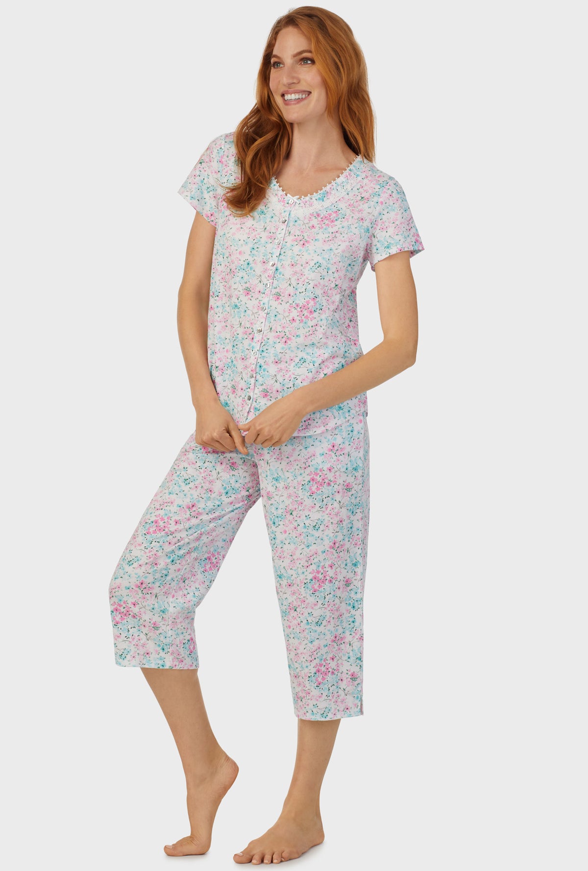 A lady wearing multi color short sleeve capri pant pj set with aqua and pink floral print.