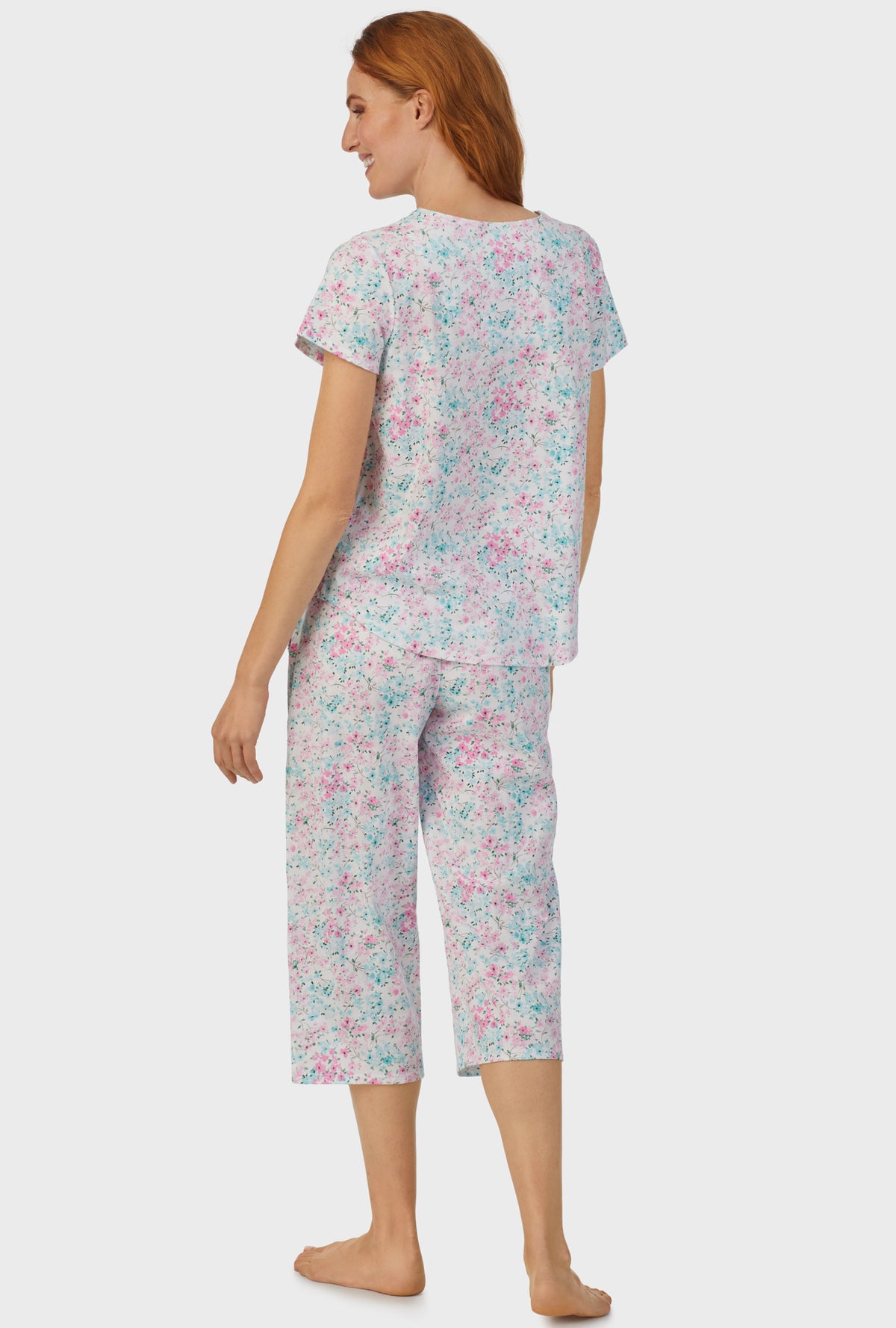 A lady wearing multi color short sleeve capri pant pj set with aqua and pink floral print.