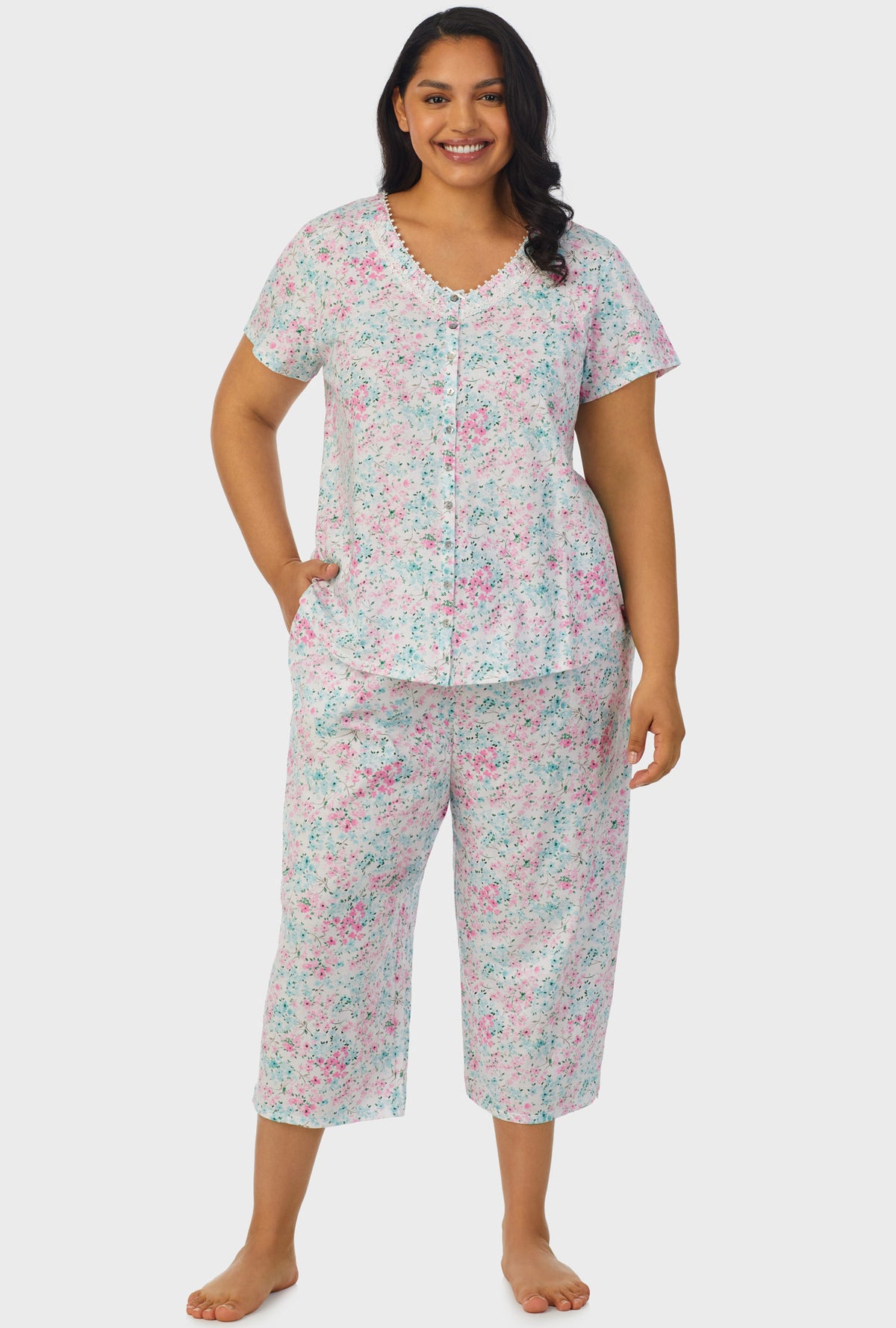 A lady wearing multi color short sleeve capri pant plus size pj set with aqua and pink floral print.