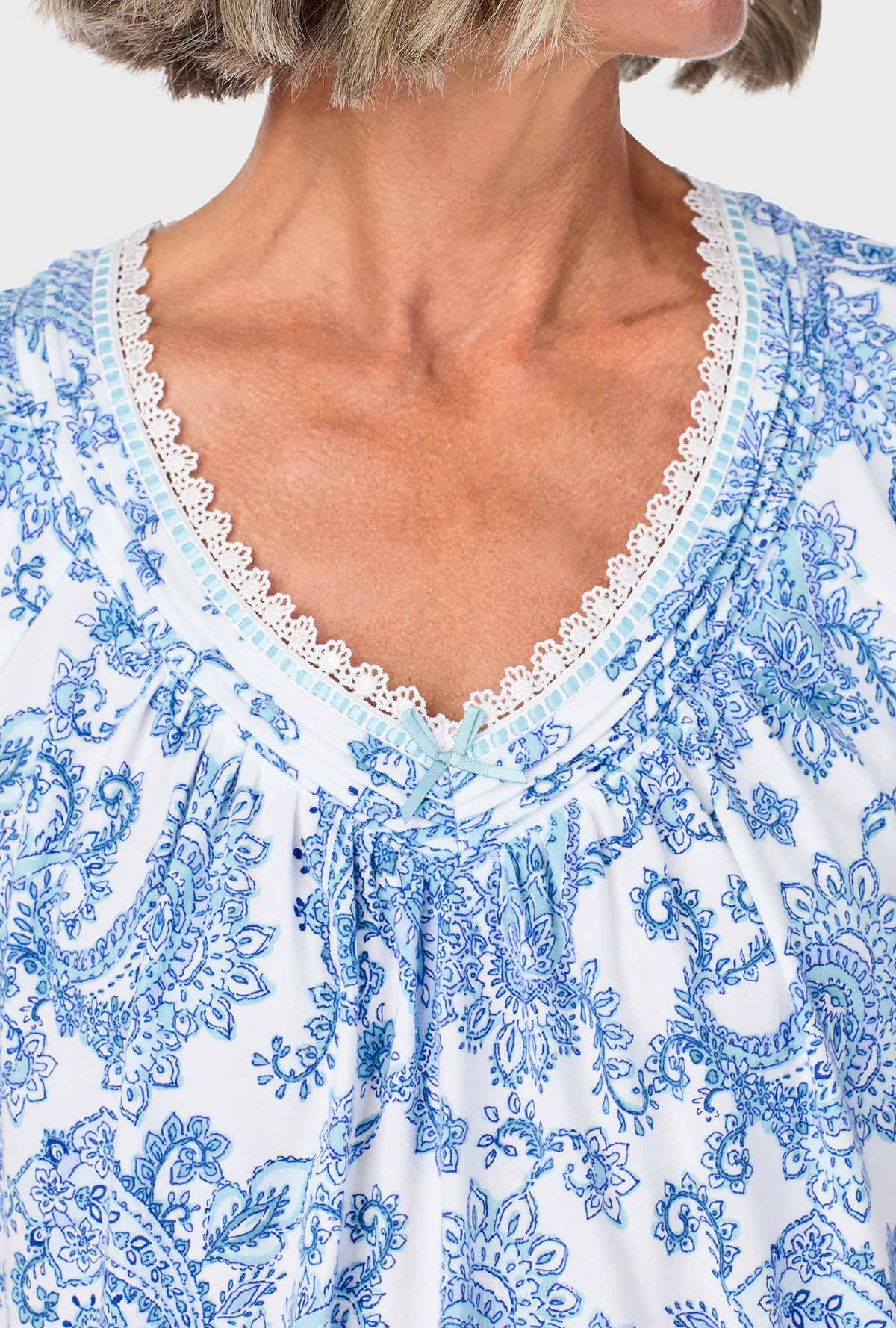 A lady wearing blue short sleeve sleepshirt with cool multi paisley print.